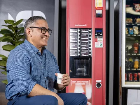Hombre tomando café de la máquina expendedora
