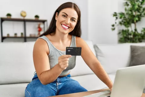 Mujer sonriendo sosteniendo tarjeta de crédito Colsubsidio.