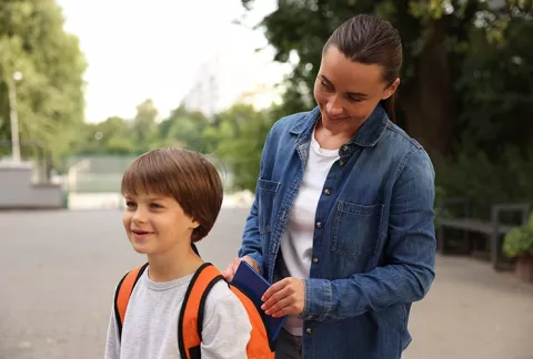 Madre guardando un cuaderno a su hijo que va al colegio.