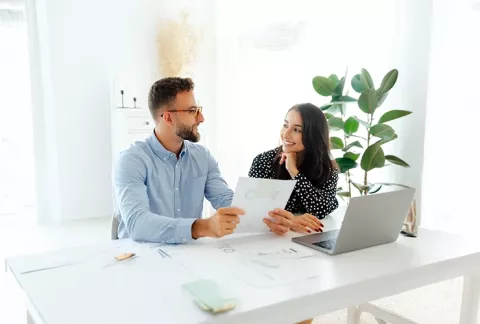 Mujer y hombre sonriendo revisando documentos.