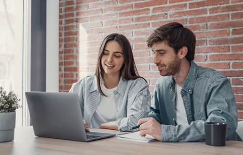 Pareja en su portátil, navegando la página web de Colsubsidio y conociendo los deportes, valores e inscripción.