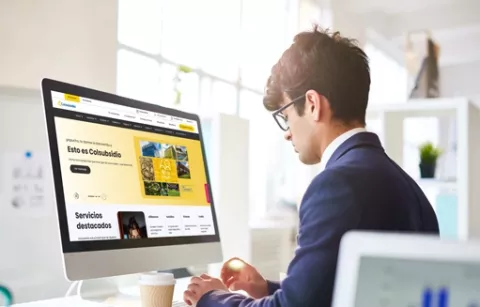 Hombre al frente del computador navegando la página web de Colsubsidio.