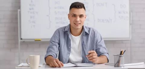 Joven sentado en un salón de clases aprendiendo inglés con Colsubsidio.