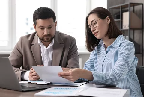 Asesora, con documentos y un portátil, afilia a una empresa a Colsubsidio.