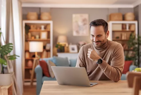 Hombre sonríe al leer un libro de ficción desde la biblioteca digital para empresas de Colsubsidio.