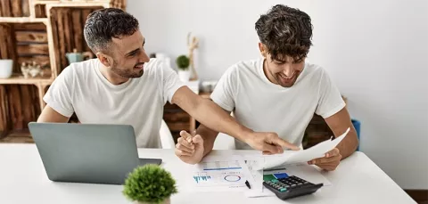 Papá e hijo revisan documentos en línea e impresos en la su estudio.