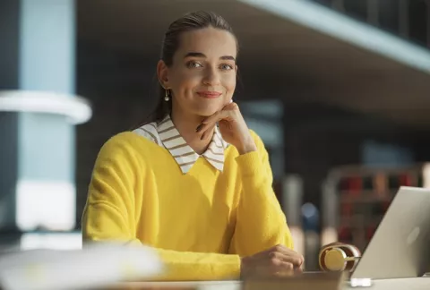 Mujer sonríe al frente de su portátil al conocer los créitos empresariales.