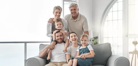 Familia, afiliada a Colsubsidio, se reúne feliz en la sala de su vivienda.