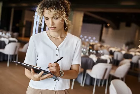 Asesora de eventos Colsubsidi opara empresas tomando nota en el salón reservado.
