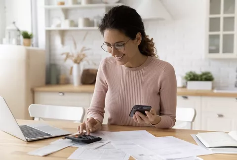 Mujer aprende tips financieros en línea, y usa la calculadora para medir sus tasa de interés.