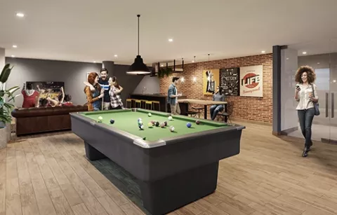 La sala lounge del conjunto Arbórea muestra a personas jugando billar.