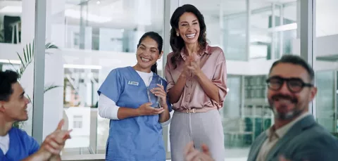 Equipo de salud médico y administrativo está reunido en una sala conversando y felices.