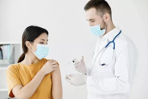 Doctor aplica inyección a una mujer en su consultorio.