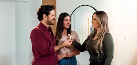Pareja recibe las llaves de su casa por parte de la asesora inmobiliaria.