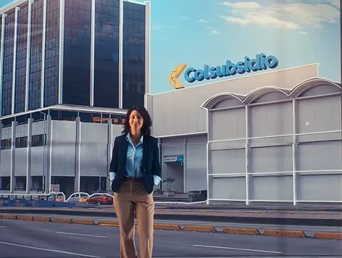 Mujer camina delante de la fachada de la sede de Colsubsidio, calle 26.