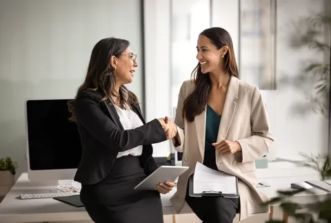 Mujeres ejecutivas se dan la mano en una oficina