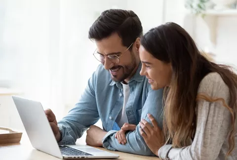 Pareja, en su portátil, viendo los webinar de vivienda Colsubsidio. 
