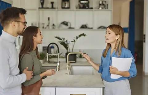 Pareja recorre el apartamento modelo con asesora inmobiliaria