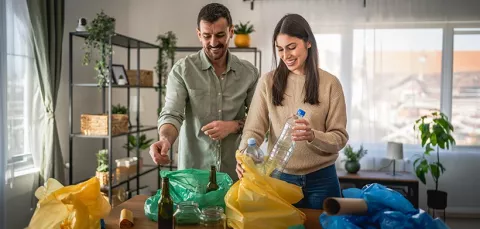 Pareja recicla residuos y los separa en bolsas de colores.