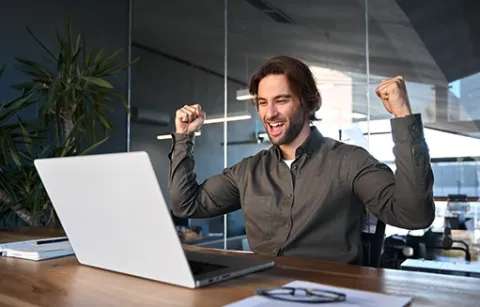 Trabajador de Colsubsidio celebra al frente de su computador.