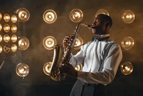Hombre tocando el saxofón en escenario.