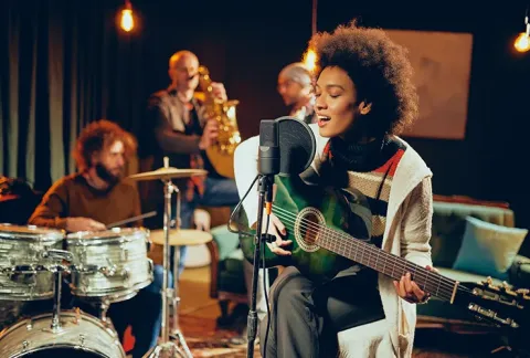 Artistas cantando con saxofonista y guitarra.