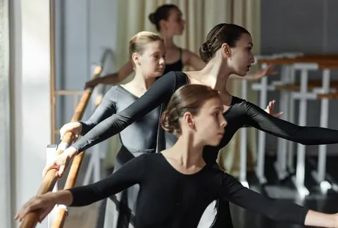 Los bailarines en una clase de ballet están practicando sus movimientos.