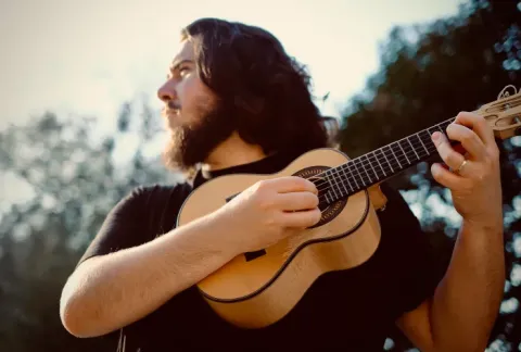 Un hombre que toca una guitarra bajo el sol