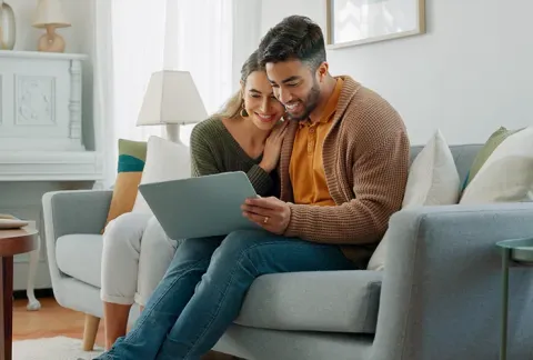 Pareja sentada en un sofa viendo el computador