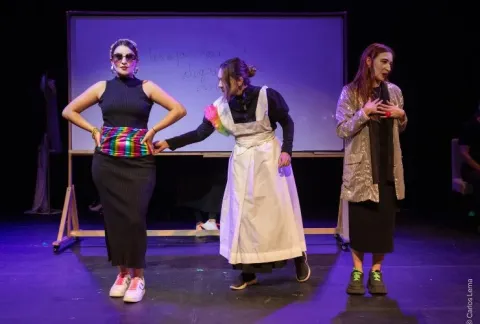 Tres mujeres con delantales y vestidos suben a un escenario.