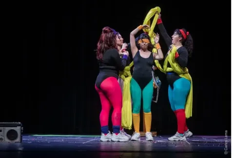 Tres mujeres con medias coloridas bailan en un escenario