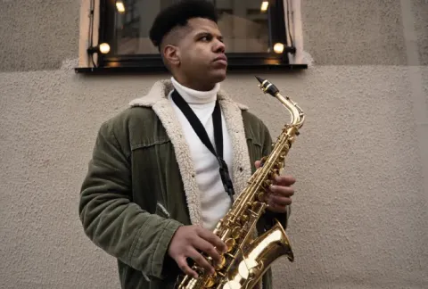 Hombre con una chaqueta verde tocando un saxofón