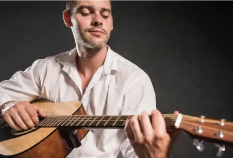 Hombre con camisa blanca tocando una guitarra