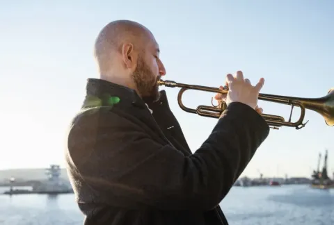 Hombre tocando la trompeta en un barco en el agua