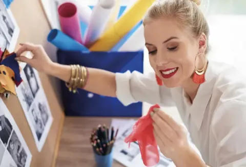 Mujer con camisa blanca poniendo papel de seda rojo en el tablón de anuncios