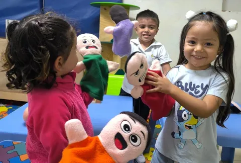 Niñas juegan consus títteres en el jardín