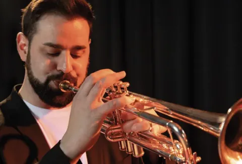 Hombre tocando una trompeta en una banda con fondo negro