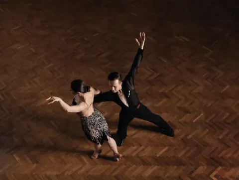 Dos personas bailan sobre un suelo de madera