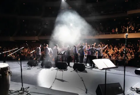 Vista de un concierto con una banda tocando en el escenario.