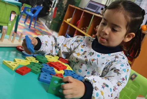 Niña juega con fichas lego en el programa de primera infancia