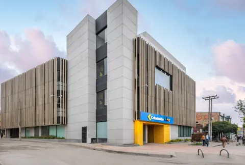 Entrada principal de BLOC Colsubsidio muestra edificios, vías y personas transitando