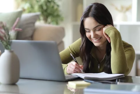 Mujer frente a un computador estudiando el programa para mujer cesante de Colsubsidio
