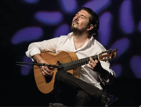 Hombre con barba tocando una guitarra en el escenario