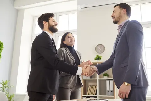 Dos personas dándose la mano en una reunión de negocios, beneficio Conexión Garantizada.
