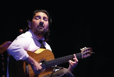 Hombre con barba tocando una guitarra en el escenario