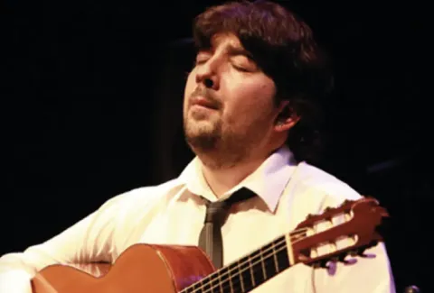 Hombre con una guitarra en las manos y una corbata
