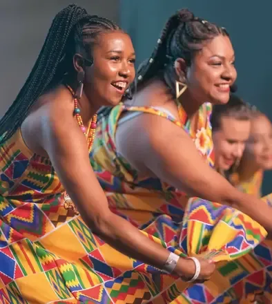 Mujeres con coloridos vestidos africanos bailando felices en el Teatro Colsubsidio.