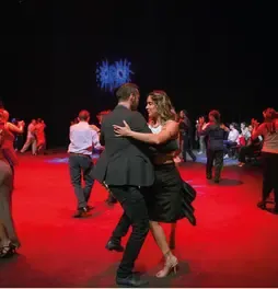 Parejas bailando tango en un escenario con luz roja en el Teatro Colsubsidio.