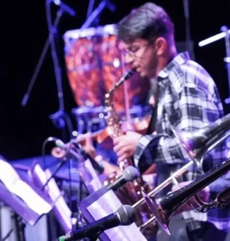 Músico con saxofón en el Teatro Colsubsidio acompañado de percusión y metales.