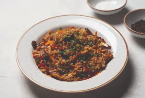 Plato de arroz frito con vegetales y hierbas servido en vajilla blanca en el Café de letras.